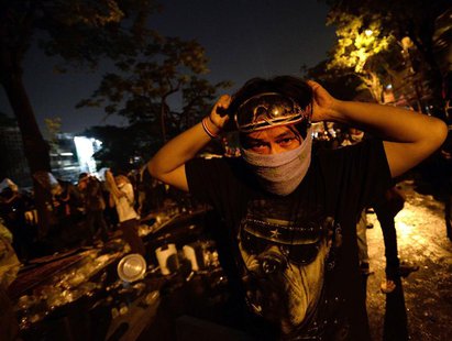 Anti-government protesters take cover from tear gas as they attack Government House during demonstrations in Bangkok December 2, 2013. REUTE Anti-government protesters take cover from tear gas as they attack Government House during demonstrations in Bangkok December 2, 2013. REUTE