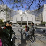 People walk past the headquarters of the People's Bank of China (PBOC), the central bank, as two paramilitary police officials patrol around People walk past the headquarters of the People's Bank of China (PBOC), the central bank, as two paramilitary police officials patrol around