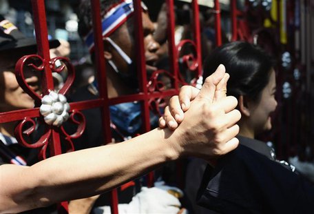 An anti-government protester touches the hand of a police officer through the main gate of the Thai Police Headquarters in Bangkok December An anti-government protester touches the hand of a police officer through the main gate of the Thai Police Headquarters in Bangkok December