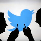 Men are silhouetted against a video screen with a Twitter logo as he poses with a Samsung S4 smartphone in this photo illustration taken in Men are silhouetted against a video screen with a Twitter logo as he poses with a Samsung S4 smartphone in this photo illustration taken in