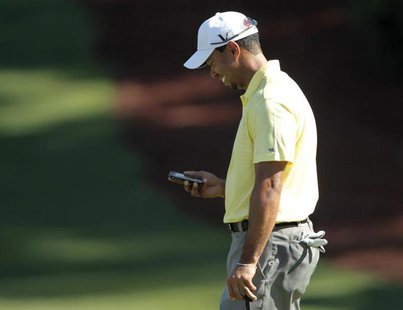 Tiger Woods of the U.S. looks at his iPhone after using it to take a picture of playing partner Mark O'Meara on the 10th green, during a pra Tiger Woods of the U.S. looks at his iPhone after using it to take a picture of playing partner Mark O'Meara on the 10th green, during a pra