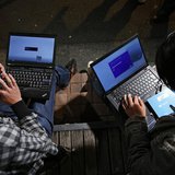 Men install Microsoft Corp's Windows 8 operating system on their laptops, as Windows 8 goes on sale after midnight, along a street at the Ak Men install Microsoft Corp's Windows 8 operating system on their laptops, as Windows 8 goes on sale after midnight, along a street at the Ak