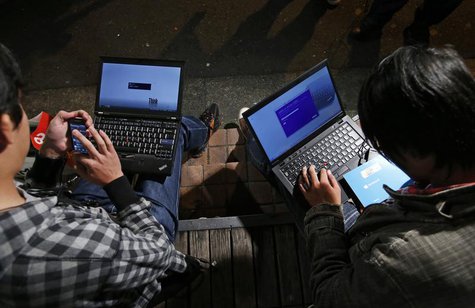 Men install Microsoft Corp's Windows 8 operating system on their laptops, as Windows 8 goes on sale after midnight, along a street at the Ak Men install Microsoft Corp's Windows 8 operating system on their laptops, as Windows 8 goes on sale after midnight, along a street at the Ak