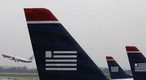 U.S. Airways jets are lined up at Reagan National Airport as an American Airlines jet takes off on the day U.S. Airways' stockholders are ex U.S. Airways jets are lined up at Reagan National Airport as an American Airlines jet takes off on the day U.S. Airways' stockholders are ex