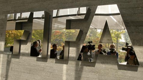 Journalists are reflected in a logo at the FIFA headquarters after a meeting of the executive committee in Zurich October 4, 2013. REUTERS/A Journalists are reflected in a logo at the FIFA headquarters after a meeting of the executive committee in Zurich October 4, 2013. REUTERS/A