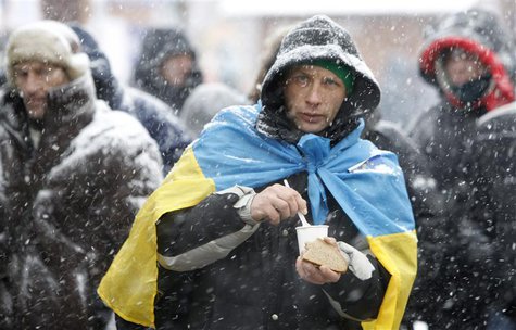 A protester holds a piece of bread as he gathers with others at Independence Square during a rally to support EU integration in Kiev Decembe A protester holds a piece of bread as he gathers with others at Independence Square during a rally to support EU integration in Kiev Decembe