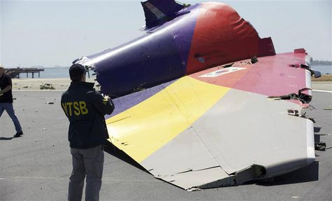 A National Transportation Safety Board (NTSB) investigator looks at the tail section of the Asiana Airlines Flight 214 that crashed at San F A National Transportation Safety Board (NTSB) investigator looks at the tail section of the Asiana Airlines Flight 214 that crashed at San F
