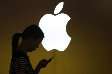 A woman looks at the screen of her mobile phone in front of an Apple logo outside its store in downtown Shanghai September 10, 2013 file pho A woman looks at the screen of her mobile phone in front of an Apple logo outside its store in downtown Shanghai September 10, 2013 file pho