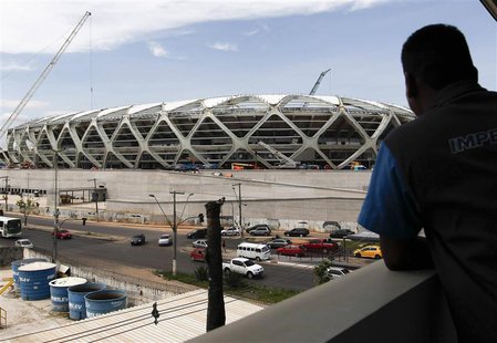 A worker observes the Arena Amazonia stadium under construction to host several 2014 World Cup soccer games, in Manaus December 14, 2013. RE A worker observes the Arena Amazonia stadium under construction to host several 2014 World Cup soccer games, in Manaus December 14, 2013. RE