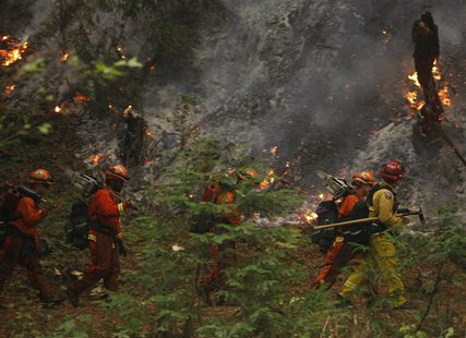 A firefighting crew walks past burning trees in Big Sur, California, December 16, 2013. REUTERS/Michael Fiala A firefighting crew walks past burning trees in Big Sur, California, December 16, 2013. REUTERS/Michael Fiala