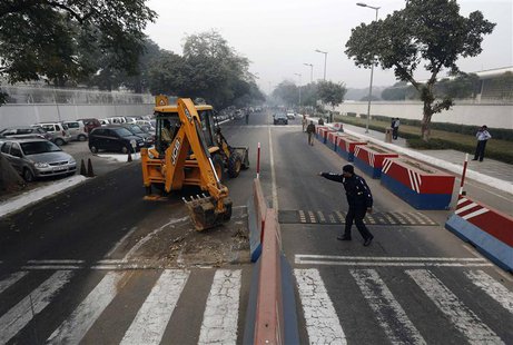 A traffic policeman guides a bulldozer removing the security barriers in front of the U.S. embassy in New Delhi December 17, 2013. REUTERS/A A traffic policeman guides a bulldozer removing the security barriers in front of the U.S. embassy in New Delhi December 17, 2013. REUTERS/A