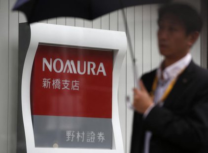 A man holding an umbrella walks past a signboard of Nomura Securities outside its branch in Tokyo October 29, 2013. REUTERS/Issei Kato A man holding an umbrella walks past a signboard of Nomura Securities outside its branch in Tokyo October 29, 2013. REUTERS/Issei Kato