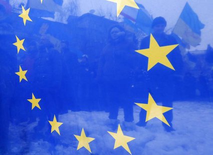 Pro-European integration protesters are seen through an EU flag during a rally near the Interior Ministry headquarters in Kiev December 17, Pro-European integration protesters are seen through an EU flag during a rally near the Interior Ministry headquarters in Kiev December 17,