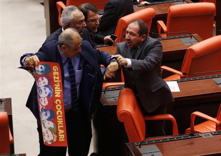 Turkey's ruling Ak Party (AKP) lawmaker Omer Faruk Oz (R) tries to stop Republican People's Party (CHP) lawmaker Musa Cam as he holds a bann Turkey's ruling Ak Party (AKP) lawmaker Omer Faruk Oz (R) tries to stop Republican People's Party (CHP) lawmaker Musa Cam as he holds a bann