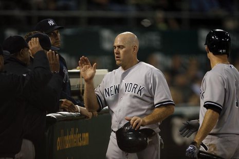 New York Yankees' Kevin Youkilis (C) high fives teammates after scoring from a single by Jayson Nix during the seventh inning against the Oa New York Yankees' Kevin Youkilis (C) high fives teammates after scoring from a single by Jayson Nix during the seventh inning against the Oa