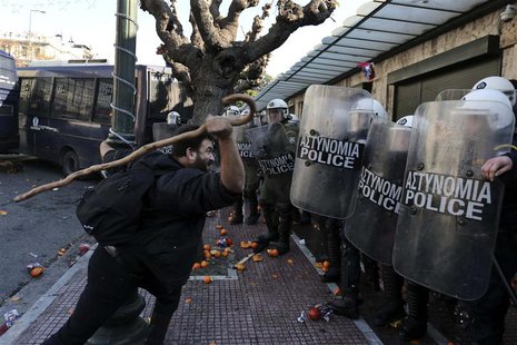 A farmer uses a stick to hit policemen during a rally against the government's new property tax outside the parliament in Athens December 20 A farmer uses a stick to hit policemen during a rally against the government's new property tax outside the parliament in Athens December 20