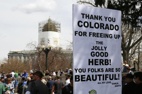 A man holds a sign referring to Colorado legalizing marijuana with the state capitol dome in the background at the 4/20 marijuana holiday in A man holds a sign referring to Colorado legalizing marijuana with the state capitol dome in the background at the 4/20 marijuana holiday in