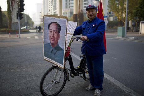 Qiu, a 65-year-old retired shipyard worker wearing a Red Army hat, poses for a photograph with his bicycle bearing a portrait of China's lat Qiu, a 65-year-old retired shipyard worker wearing a Red Army hat, poses for a photograph with his bicycle bearing a portrait of China's lat