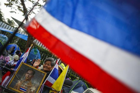 An anti-government protester sits next to a portrait of Thailand's King Bhumibol Adulyadej as she camps outside the Thai-Japan youth stadium An anti-government protester sits next to a portrait of Thailand's King Bhumibol Adulyadej as she camps outside the Thai-Japan youth stadium