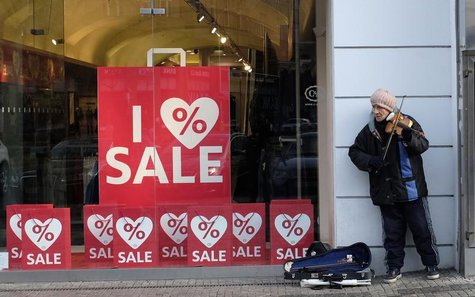 A man plays a violin in front of a shop window decorated with Christmas sales signs in Prague December 24, 2013. REUTERS/David W Cerny A man plays a violin in front of a shop window decorated with Christmas sales signs in Prague December 24, 2013. REUTERS/David W Cerny