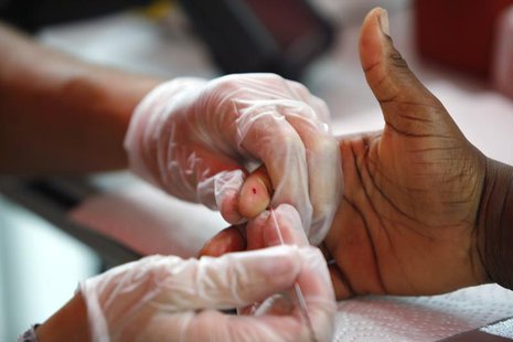 A medical technician draws a blood sample to screen for glucose and cholesterol at a free health screening as part of the National Urban Lea A medical technician draws a blood sample to screen for glucose and cholesterol at a free health screening as part of the National Urban Lea