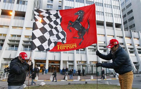 Fans fix a Ferrari flag in the ground in front of the CHU Nord hospital emergency unit in Grenoble, French Alps, where retired seven-times F Fans fix a Ferrari flag in the ground in front of the CHU Nord hospital emergency unit in Grenoble, French Alps, where retired seven-times F