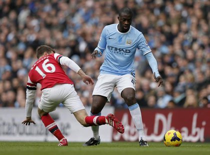Manchester City's Yaya Toure (R) is challenged by Arsenal's Aaron Ramsey during their English Premier League soccer match at the Etihad stad Manchester City's Yaya Toure (R) is challenged by Arsenal's Aaron Ramsey during their English Premier League soccer match at the Etihad stad