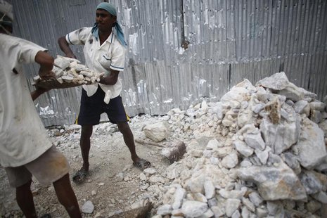 A worker helps his colleague to lift a bucket of limestone as they work in a stone crushing factory at Burimari in Lalmonirhat district July A worker helps his colleague to lift a bucket of limestone as they work in a stone crushing factory at Burimari in Lalmonirhat district July