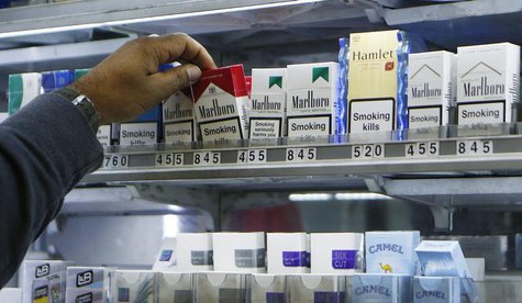 A shopkeeper reaches for a packet of cigarettes in a newsagent in London November 28, 2013. REUTERS/Suzanne Plunkett A shopkeeper reaches for a packet of cigarettes in a newsagent in London November 28, 2013. REUTERS/Suzanne Plunkett
