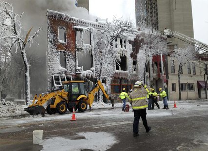 Emergency workers stand outside an apartment building which was destroyed by an explosion and a fire in Minneapolis January 1, 2014. REUTERS Emergency workers stand outside an apartment building which was destroyed by an explosion and a fire in Minneapolis January 1, 2014. REUTERS