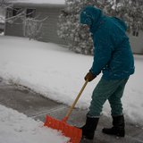 A man shovels snow off a sidewalk. A man shovels snow off a sidewalk.