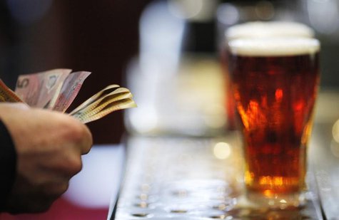 A customer pays for a Fosters beer at the Occidental Hotel in central Sydney June 21, 2011. REUTERS/Tim Wimborne A customer pays for a Fosters beer at the Occidental Hotel in central Sydney June 21, 2011. REUTERS/Tim Wimborne