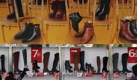 A customer picks up a shoe at a shop where posters advertising price discounts are hung, outside a department store in Beijing, October 23, A customer picks up a shoe at a shop where posters advertising price discounts are hung, outside a department store in Beijing, October 23,
