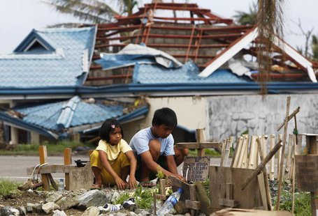 Romualdo Redona and his younger sister Angel offer prayers and candles at the grave of their siblings, who were victims of the onslaught of Romualdo Redona and his younger sister Angel offer prayers and candles at the grave of their siblings, who were victims of the onslaught of