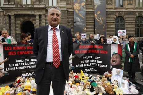 Syrian opposition member Dr. Kamal al-Labwani stand by a banner and children's stuffed toys at a demonstration near the Louvre Museum in Par Syrian opposition member Dr. Kamal al-Labwani stand by a banner and children's stuffed toys at a demonstration near the Louvre Museum in Par