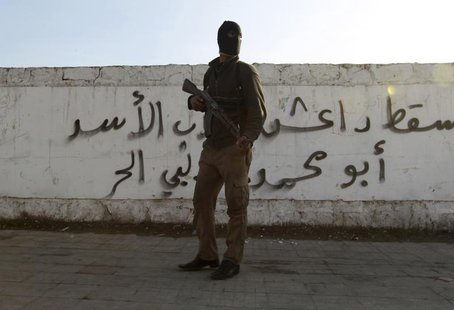 A Free Syrian Army fighter carries his weapon as he stands in front of graffiti that reads "Daesh (Islamic State of Iraq and the Levant ) do A Free Syrian Army fighter carries his weapon as he stands in front of graffiti that reads "Daesh (Islamic State of Iraq and the Levant ) do