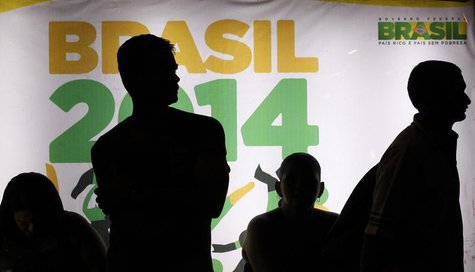 People are silhouetted in front of an advertisement of the Brazil 2014 FIFA Soccer World Cup as they wait for a bus in Recife June 21, 2013. People are silhouetted in front of an advertisement of the Brazil 2014 FIFA Soccer World Cup as they wait for a bus in Recife June 21, 2013.