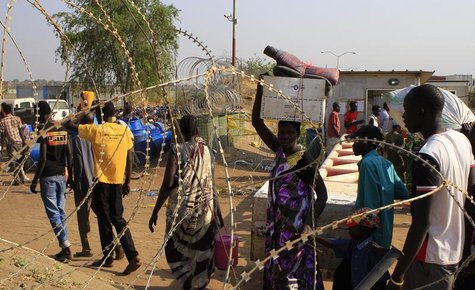 Displaced people walk past razor wire at Tomping camp, where some 15,000 displaced people who fled their homes are sheltered by the United N Displaced people walk past razor wire at Tomping camp, where some 15,000 displaced people who fled their homes are sheltered by the United N