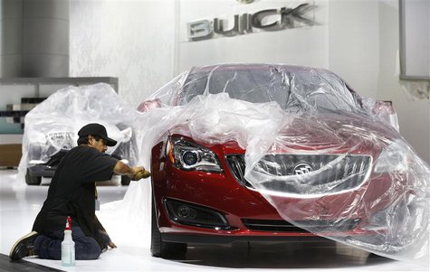 Auto show worker Jorge Martinez details a General Motors 2014 Buick Regal vehicle under wraps, as they prepare the displays for the media pr Auto show worker Jorge Martinez details a General Motors 2014 Buick Regal vehicle under wraps, as they prepare the displays for the media pr