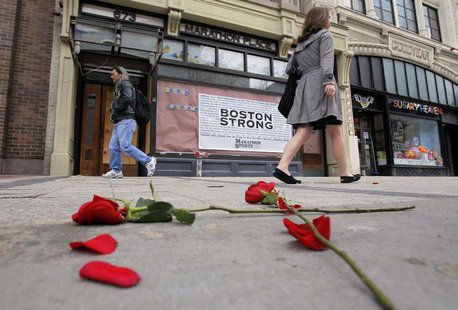 Flowers lie on the sidewalk at the site of the first explosion as people walk along Boylston Street after the street reopened to the public Flowers lie on the sidewalk at the site of the first explosion as people walk along Boylston Street after the street reopened to the public