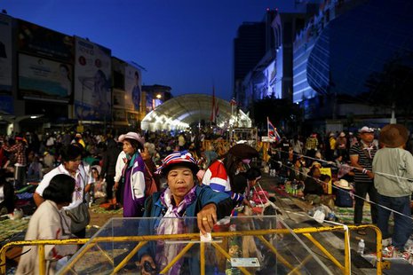 An anti-government protester gives donation as others wake up in their encampment built between shopping malls in central Bangkok January 15 An anti-government protester gives donation as others wake up in their encampment built between shopping malls in central Bangkok January 15