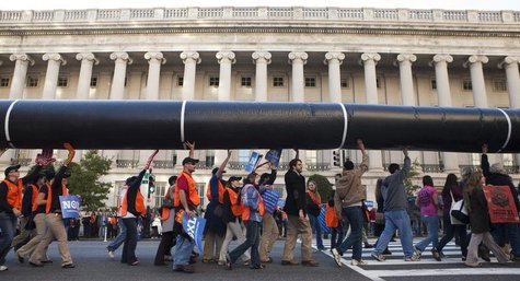 Demonstrators carry a giant mock pipeline while calling for the cancellation of the Keystone XL pipeline during a rally in front of the Whit Demonstrators carry a giant mock pipeline while calling for the cancellation of the Keystone XL pipeline during a rally in front of the Whit