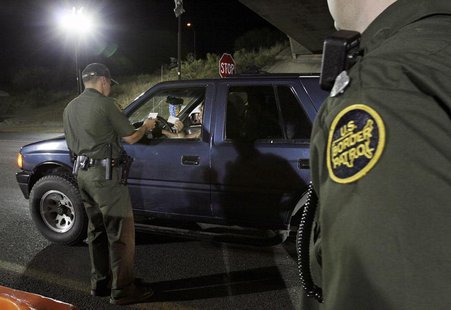 A U.S. Border Patrol agent checks the identification of a motorist at a checkpoint 20 miles north of the United States and Mexican border ne A U.S. Border Patrol agent checks the identification of a motorist at a checkpoint 20 miles north of the United States and Mexican border ne