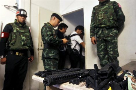 Soldiers stand next to a cache of weapons found in an derelict building where military forces say an explosive device was thrown on to anti- Soldiers stand next to a cache of weapons found in an derelict building where military forces say an explosive device was thrown on to anti-
