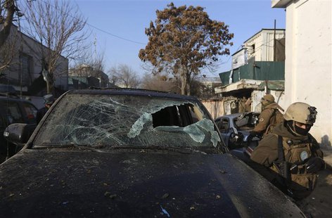 Afghan security forces walk near a damaged vehicle outside a Lebanese restaurant, the site of a suicide attack, in Kabul January 18, 2014. R Afghan security forces walk near a damaged vehicle outside a Lebanese restaurant, the site of a suicide attack, in Kabul January 18, 2014. R