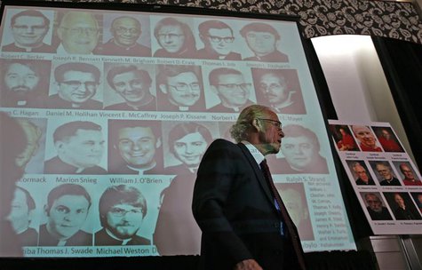 Attorney Jeff Anderson walks by a projection of photographs of priests at a news conference where thousands of documents on victims of sexua Attorney Jeff Anderson walks by a projection of photographs of priests at a news conference where thousands of documents on victims of sexua