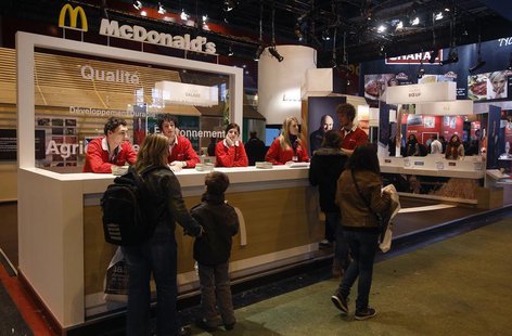 People walk past a McDonald's fast food stand at the 49th Paris International Farm Show at the Porte de Versailles exhibition center in Pari People walk past a McDonald's fast food stand at the 49th Paris International Farm Show at the Porte de Versailles exhibition center in Pari