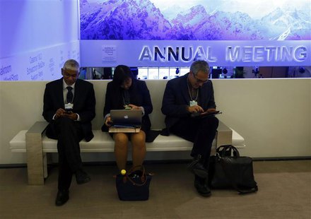 Participants use their smart phones and laptops as they sit on a bench between sessions during the annual meeting of the World Economic Foru Participants use their smart phones and laptops as they sit on a bench between sessions during the annual meeting of the World Economic Foru