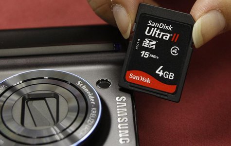 A shopper poses with a SanDisk memory card beside a Samsung camera in Hong Kong September 17, 2008. REUTERS/Bobby Yip A shopper poses with a SanDisk memory card beside a Samsung camera in Hong Kong September 17, 2008. REUTERS/Bobby Yip