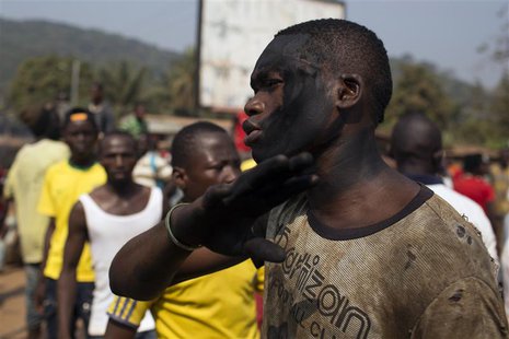 A man with charcoal smeared on his face reacts as a crowd barricades a street during a dispute between members of the local Christian commun A man with charcoal smeared on his face reacts as a crowd barricades a street during a dispute between members of the local Christian commun